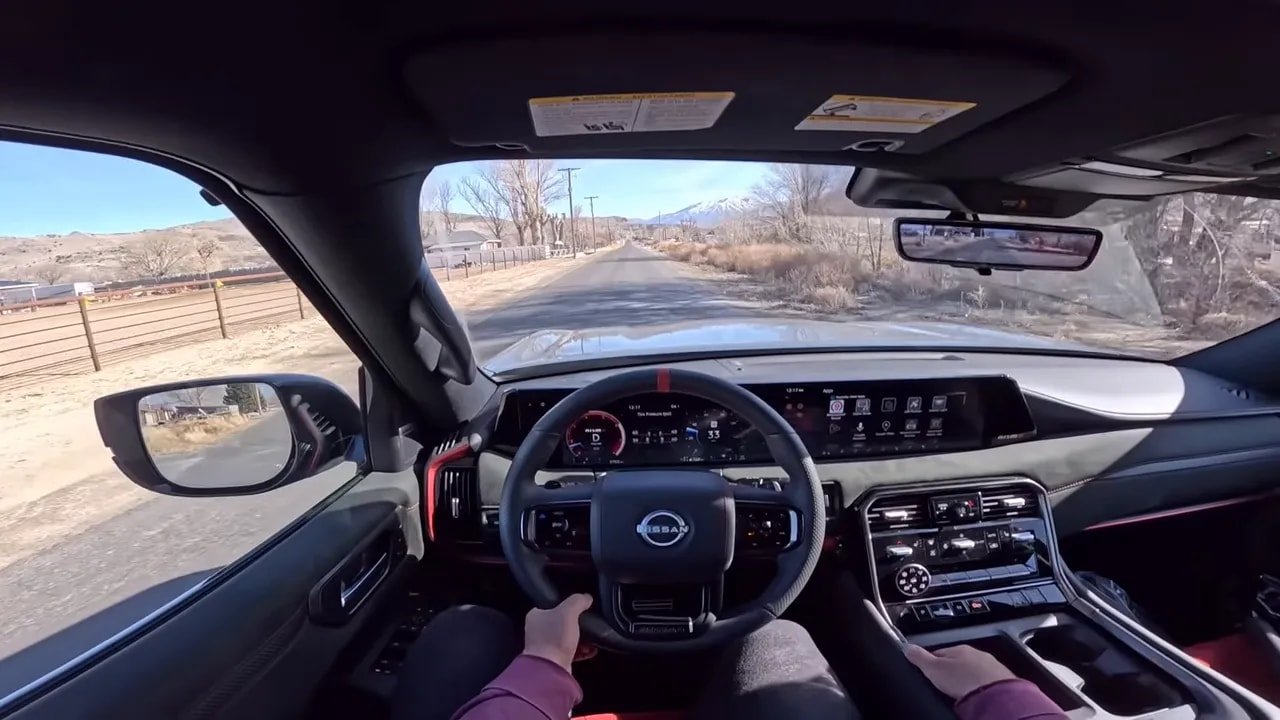 Well-exposed driver point-of-view of Nissan Armada Nismo interior showing steering wheel, digital cluster and distant mountain on the road
